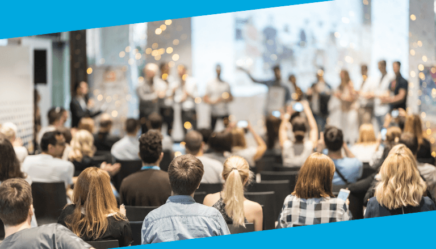 Association members celebrating an award being received on a stage at a conference.